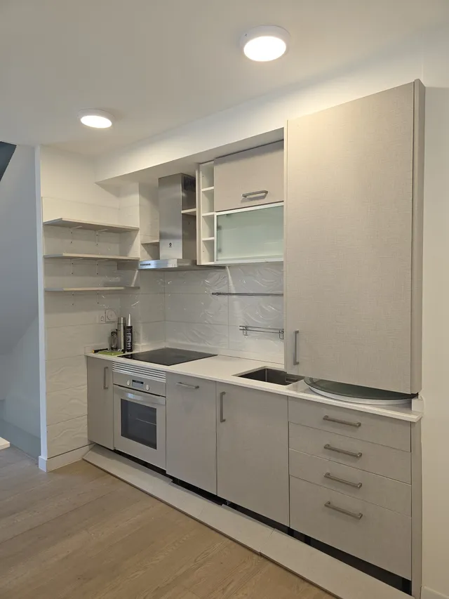 Cocina lineal con muebles altos y bajos revestidos en gris con textura textil