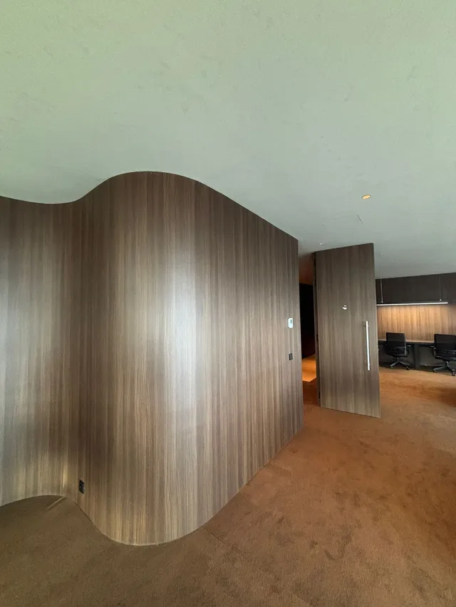 Pared curva revestida con vinilo SOIF Walnut efecto madera oscura