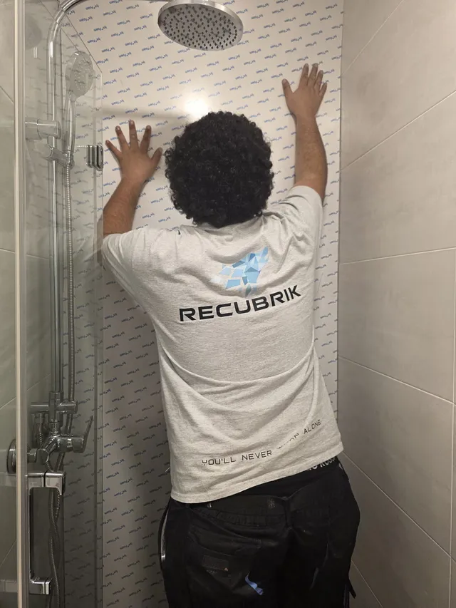 Instalador colocando el vinilo en la pared de la ducha