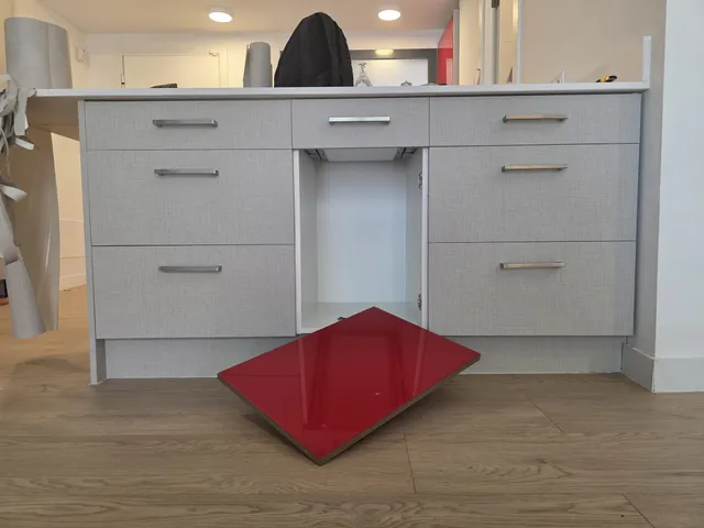 Muebles de la isla ya revestidos, con un frente rojo pendiente en el suelo