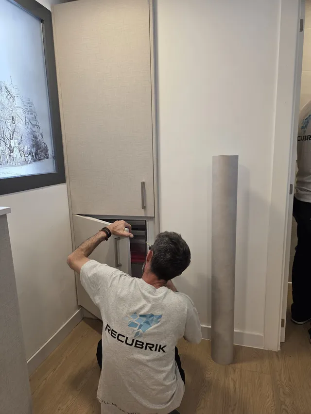 Instalador revistiendo la columna del frigorífico con el rollo de vinilo al lado
